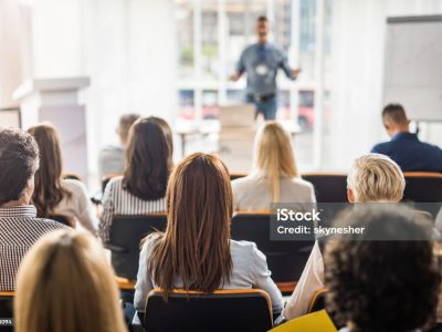 Back view of large group of business people having a training class in a board room.